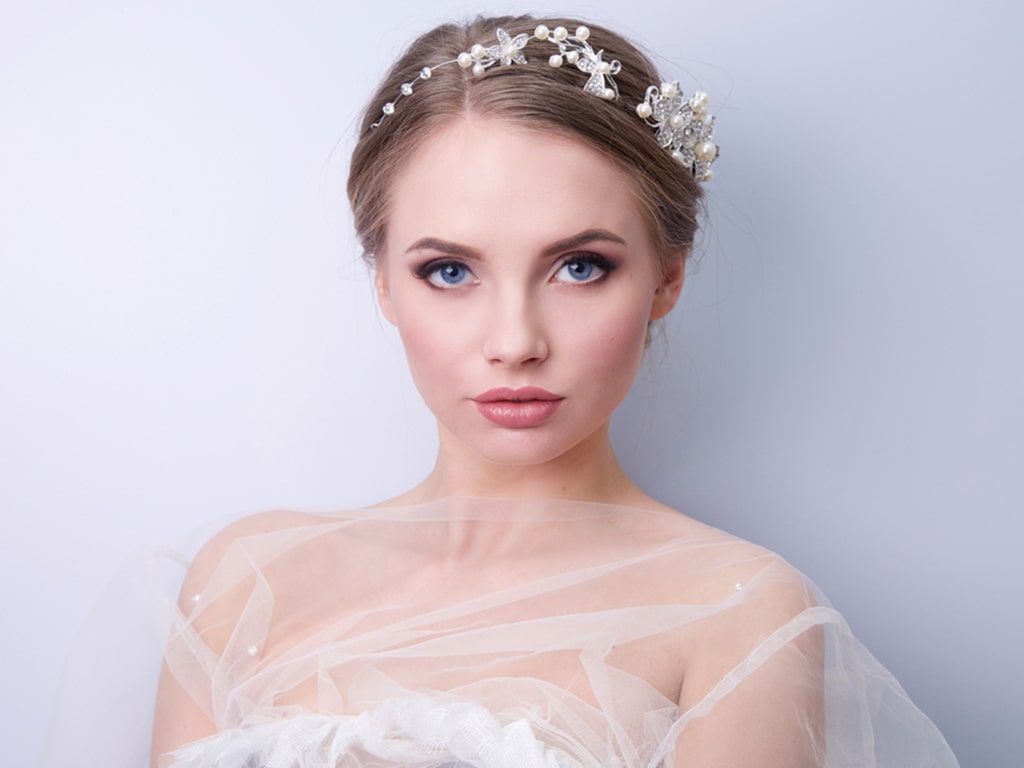 عروس زیبا با چشم‌های آبی و آرایش زیبا و تور کار شده روی یقه لباس عروس