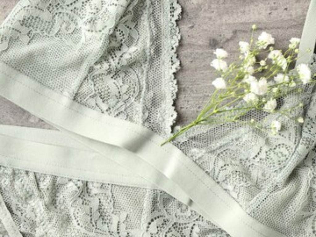ست لباس زیر گیپور بدون فنر که با رنگ طوسی زیبا در کنار گل‌ها قرار دارد. 