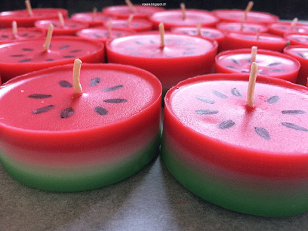تعدادی شمع استوانه‌ای به رنگ هندوانه و با ظاهری زیبا متناسب برای تزئین شب یلدا در تصویر دیده می‌شوند.