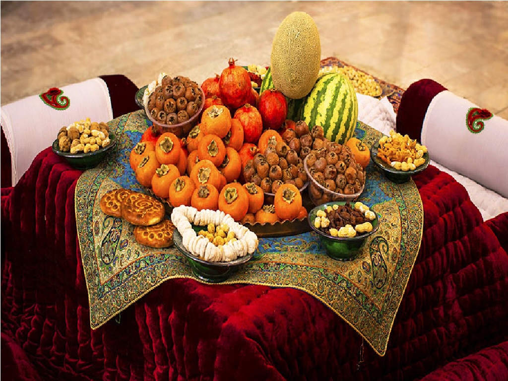 چیدمان میوه‌های متنوع و مخصوص شب یلدا روی ترمه زیبای ایرانی و کرسی قرمز رنگ تصویر زیبایی را ایجاد کرده است.