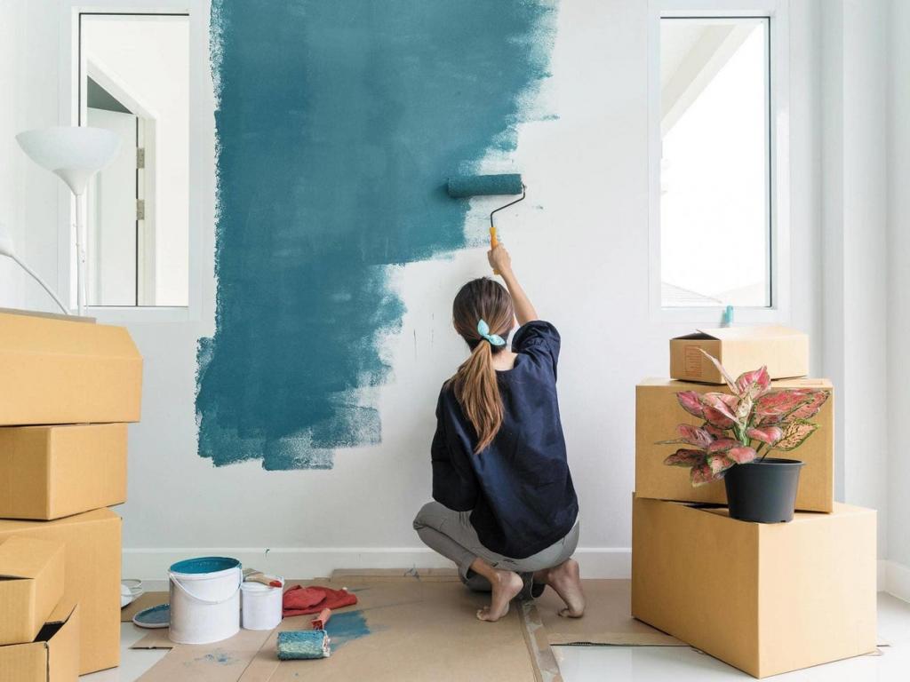 نمایی از فردی که در حال رنگ کردن قسمتی از دیوار اتاقش است.